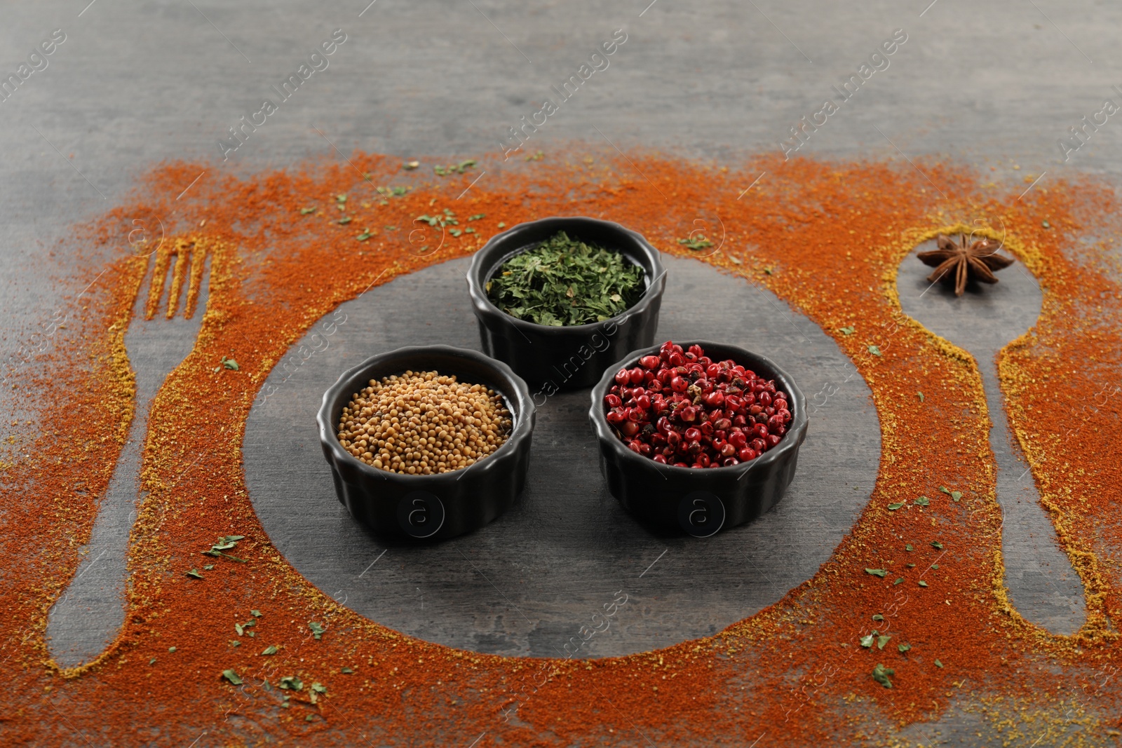 Photo of Different spices, silhouettes of cutlery and plate on grey table, closeup