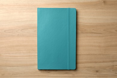 Turquoise planner on wooden table, top view