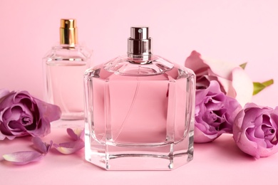Photo of Bottles of perfume and beautiful roses on pink background