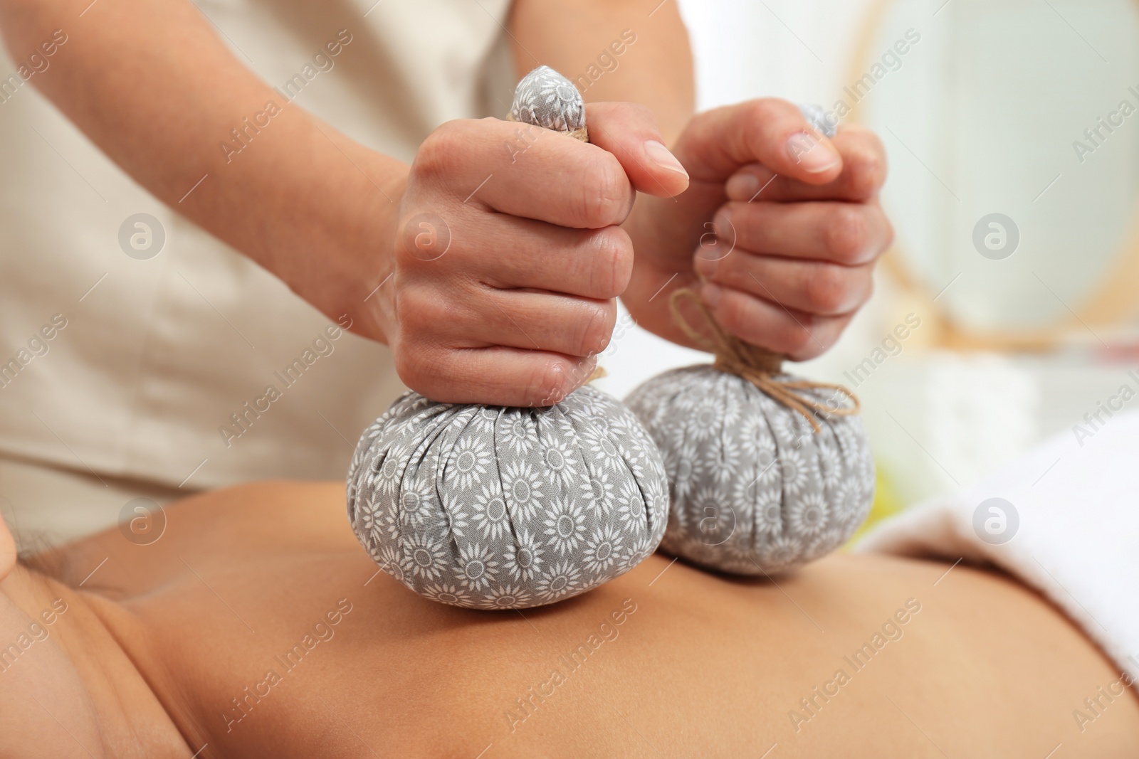 Photo of Young woman receiving herbal bag massage in spa salon, closeup