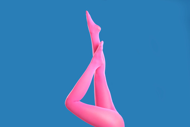 Woman wearing pink tights on blue background, closeup of legs