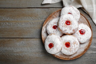 Photo of Delicious donuts with jelly and powdered sugar on wooden table, top view. Space for text