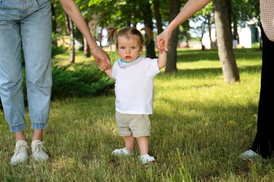 Photo of Women supporting baby girl while she learning to walk in park