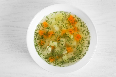 Photo of Bowl of fresh homemade soup to cure flu on wooden background, top view