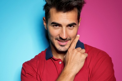 Young man with trendy hairstyle posing on color background