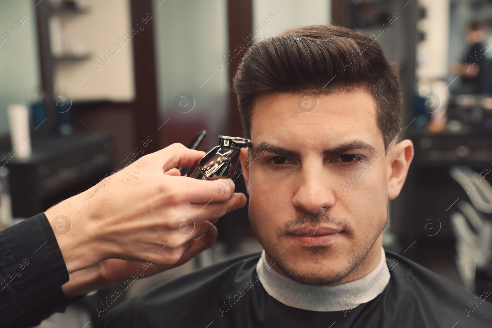 Photo of Professional hairdresser making stylish haircut in salon, closeup