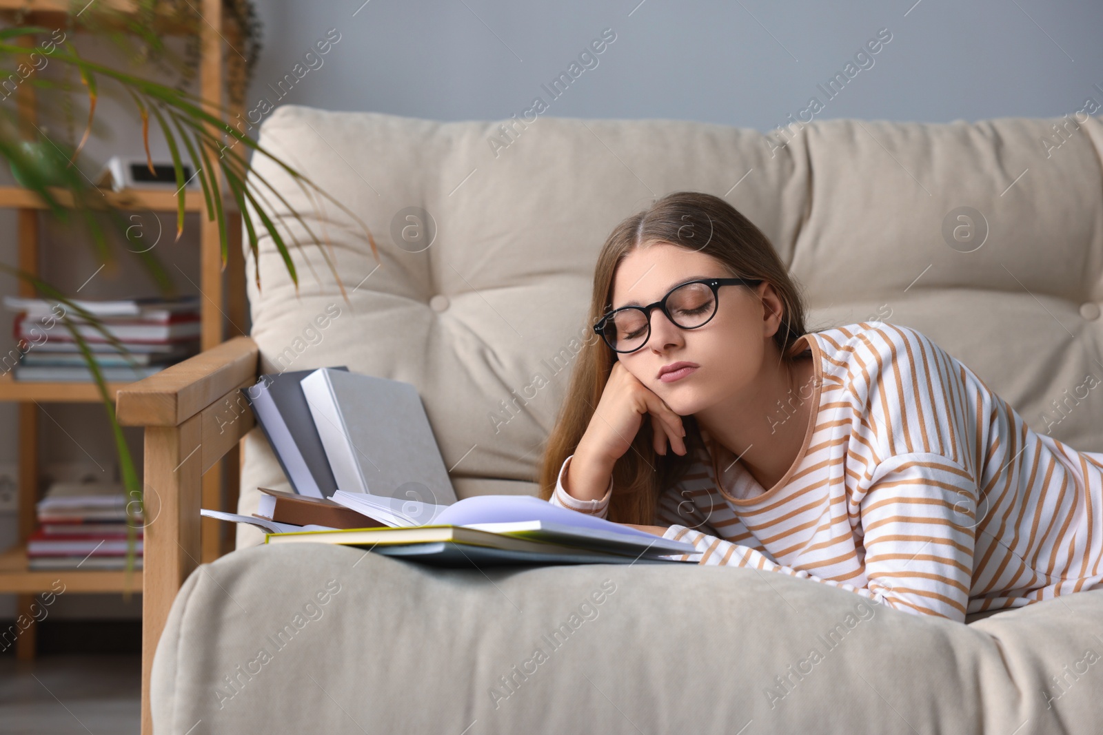 Photo of Young tired woman studying on couch indoors