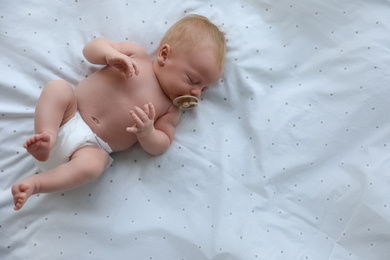 Photo of Cute newborn baby sleeping on bed, top view. Space for text