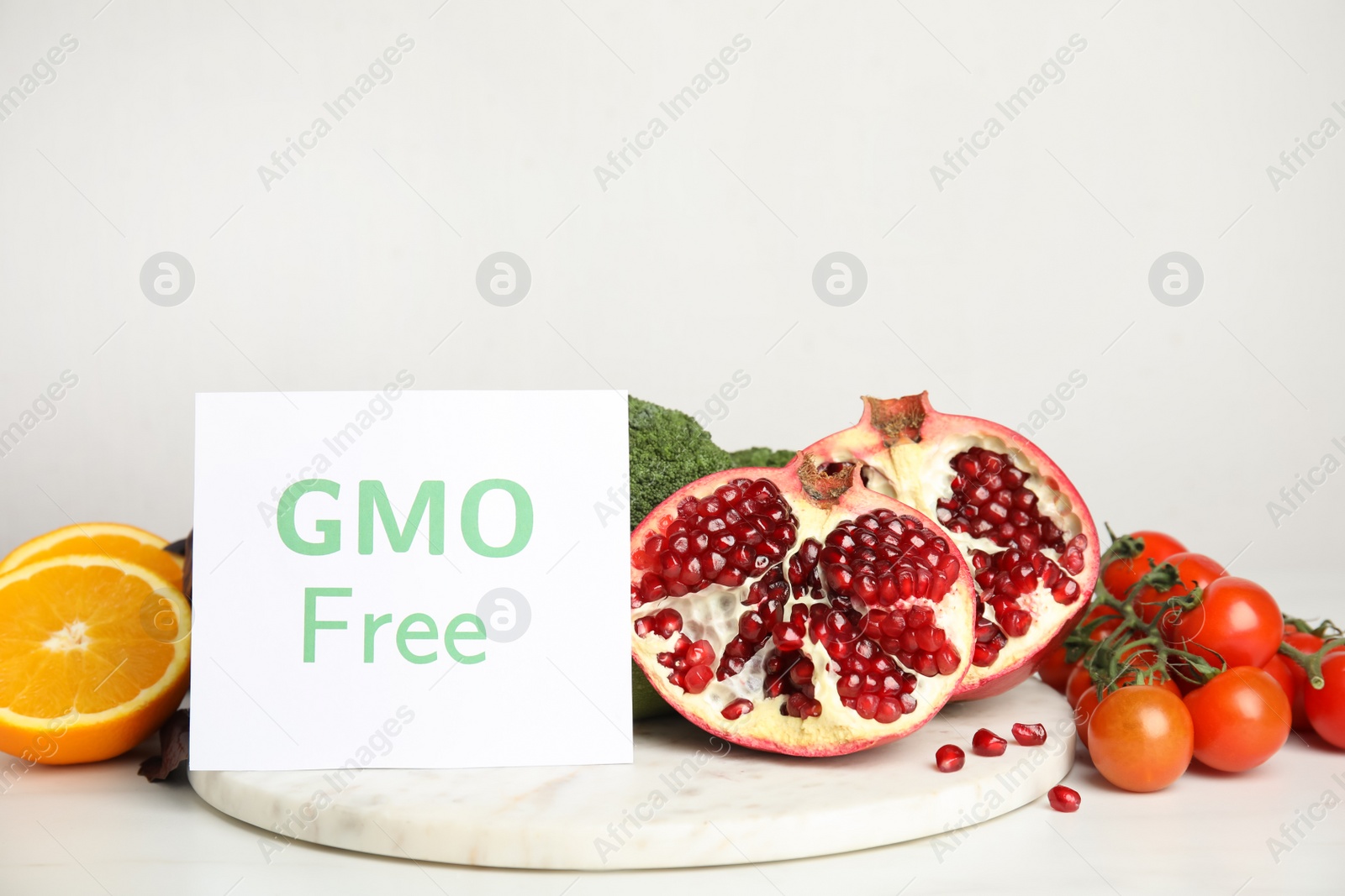 Photo of Tasty fresh GMO free products and paper card on white table