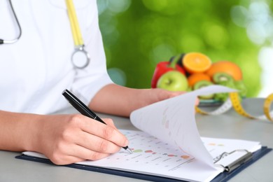 Nutritionist with list of products at table outdoors, closeup