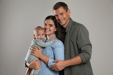 Photo of Happy family. Couple with their cute baby on grey background