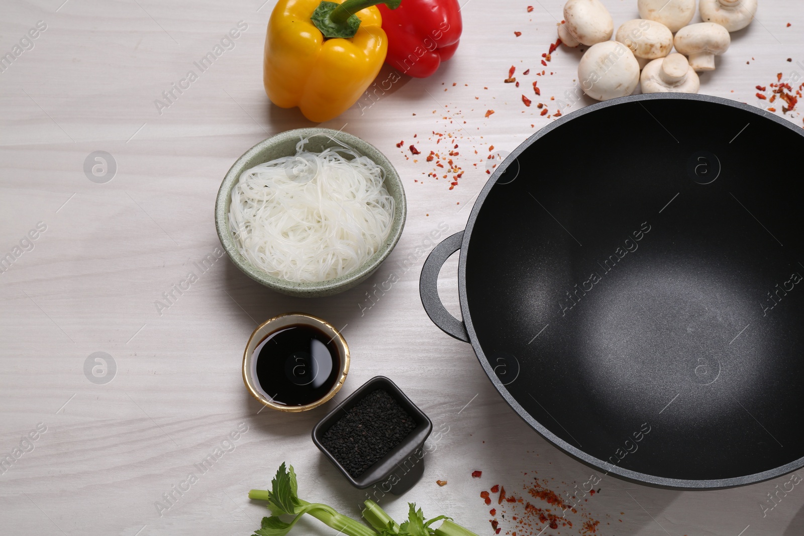 Photo of Wok and different products on white wooden table, above view. Space for text