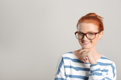 Photo of Candid portrait of happy red haired woman with charming smile on light background, space for text