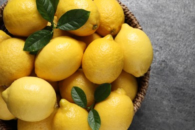 Photo of Fresh lemons in wicker basket on grey table, top view