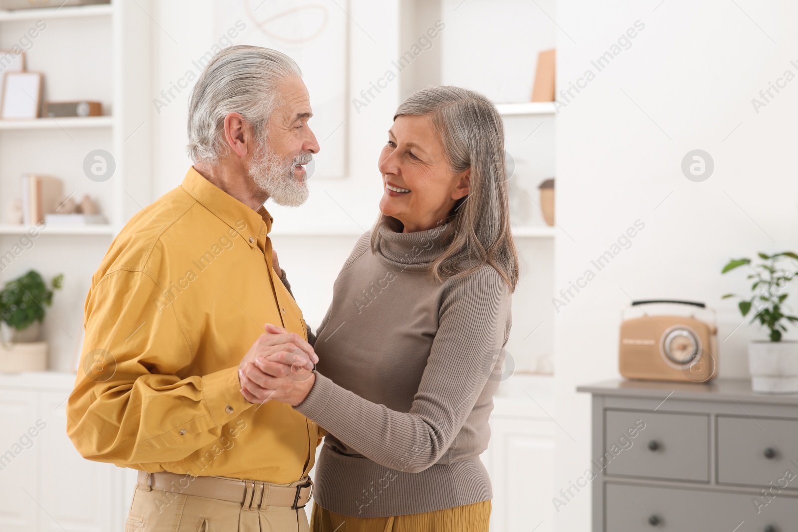 Photo of Affectionate senior couple dancing in living room at home