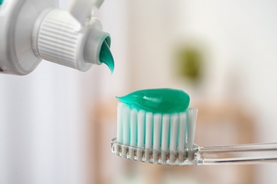 Photo of Applying paste on toothbrush against blurred background, closeup