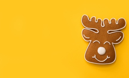 Photo of Christmas deer shaped gingerbread cookie on yellow background, top view. Space for text