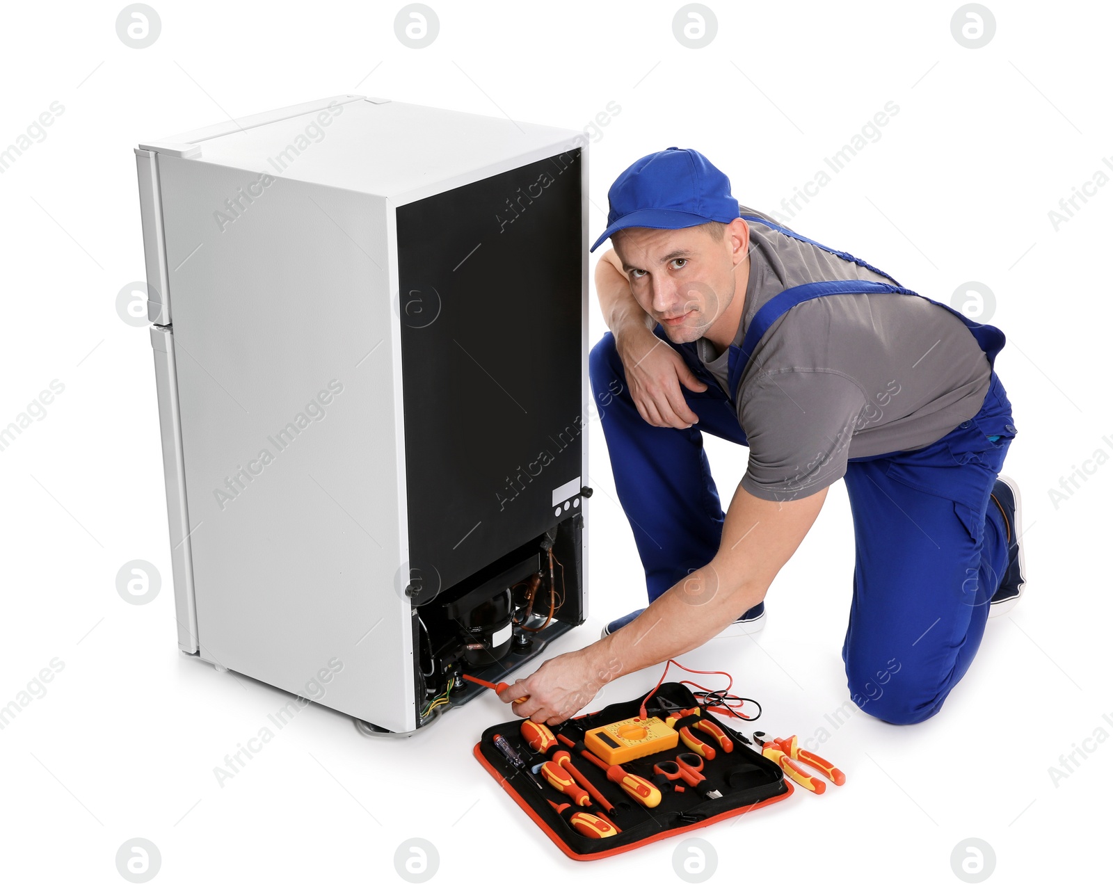 Photo of Male technician in uniform repairing refrigerator on white background