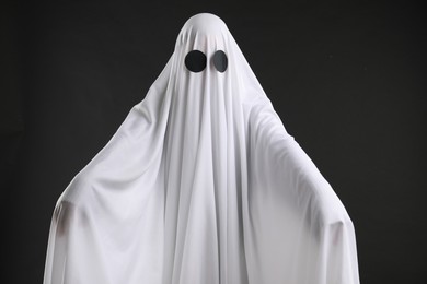 Creepy ghost. Person covered with white sheet on black background
