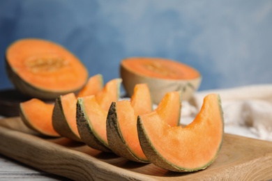 Photo of Slices of ripe cantaloupe melon in wooden tray on table