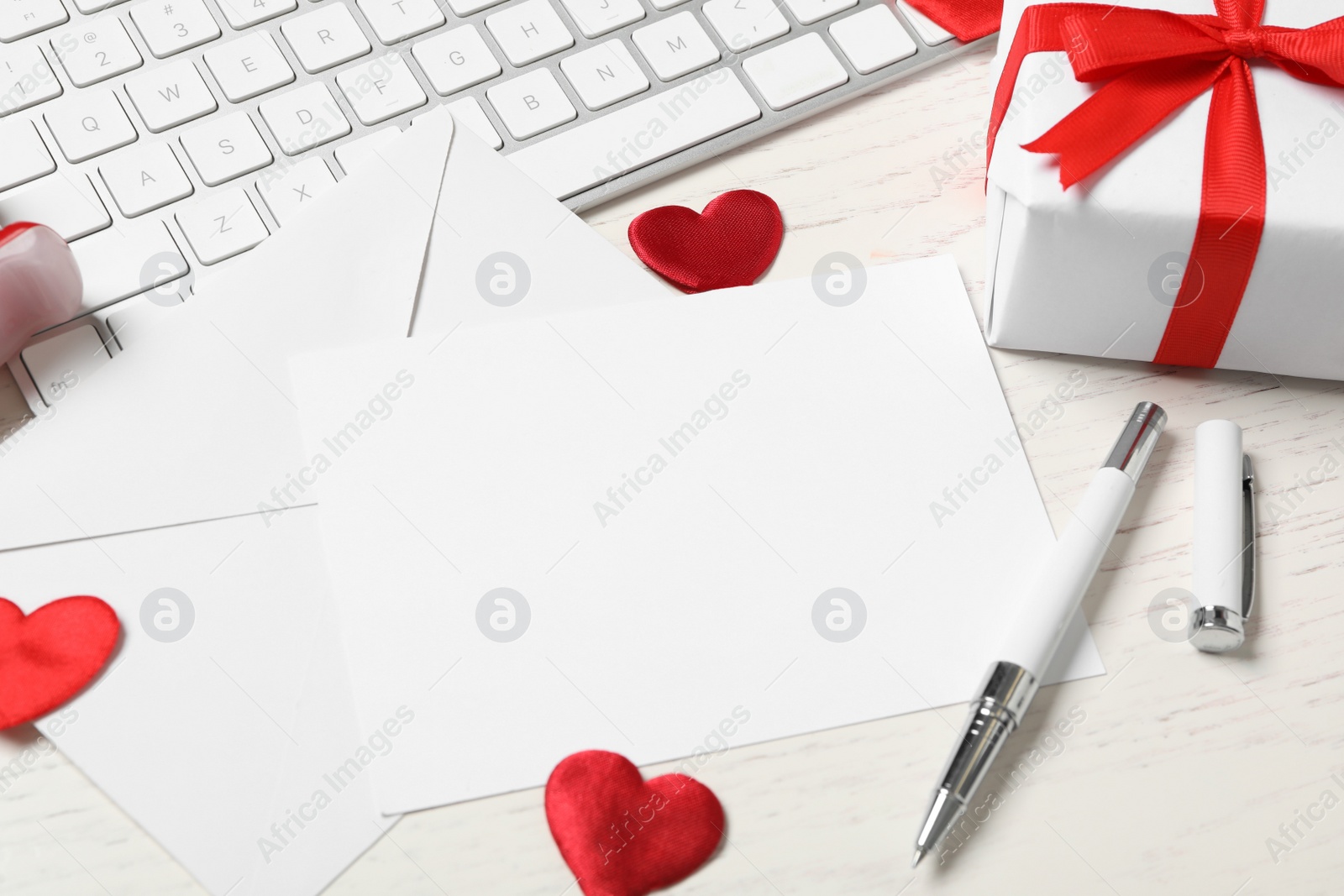 Photo of Composition with blank card on white wooden table, space for text. Valentine's Day celebration