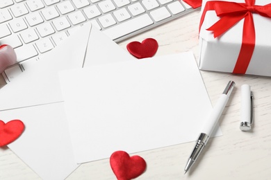 Photo of Composition with blank card on white wooden table, space for text. Valentine's Day celebration