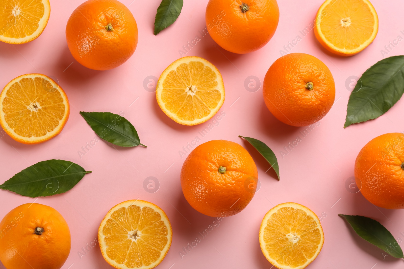 Photo of Fresh ripe oranges with green leaves on pink background, flat lay