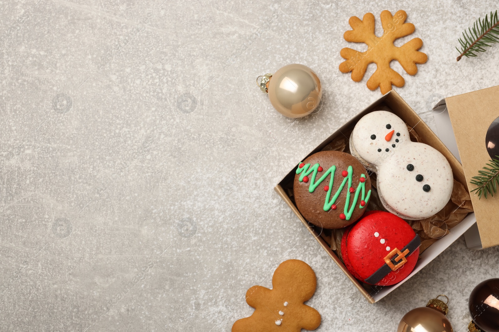 Photo of Tasty Christmas macarons in box and festive decor on table, flat lay. Space for text