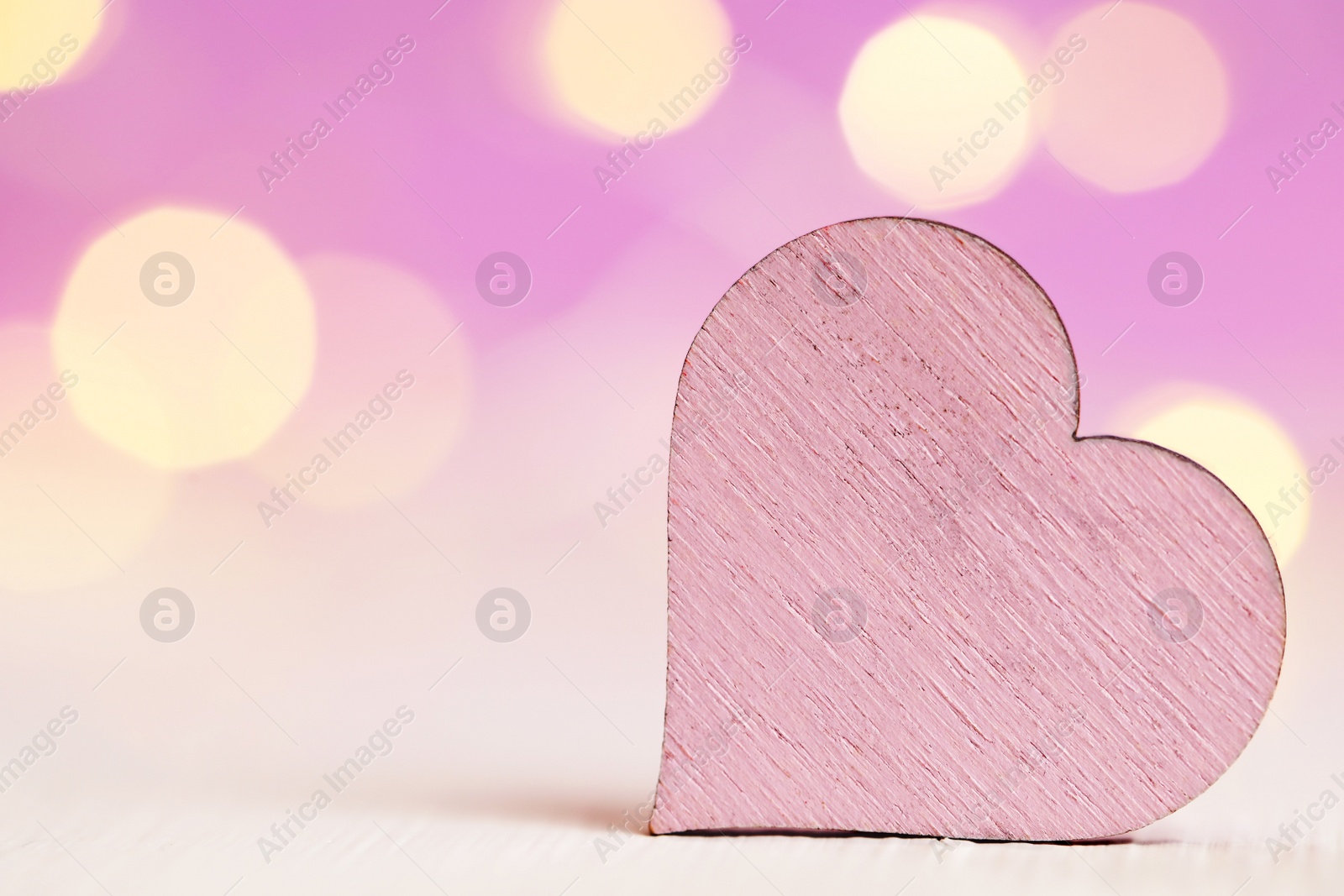 Photo of Wooden heart on white table against festive lights, space for text. St. Valentine's day