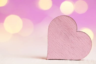 Wooden heart on white table against festive lights, space for text. St. Valentine's day