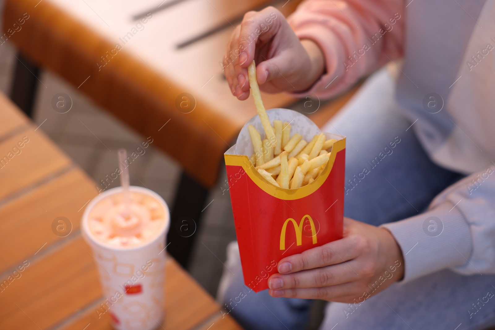 Photo of Lviv, Ukraine - September 26, 2023: Woman eating McDonald's french fries outdoors, closeup