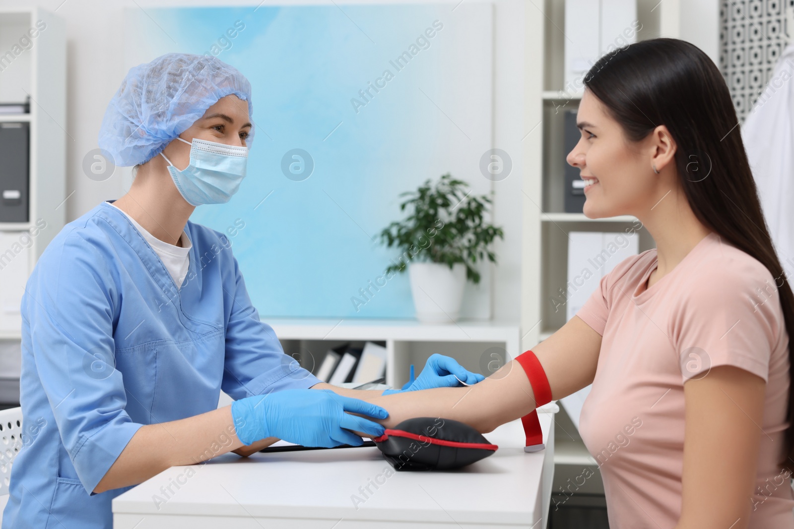 Photo of Laboratory testing. Doctor taking blood sample from patient at white table in hospital