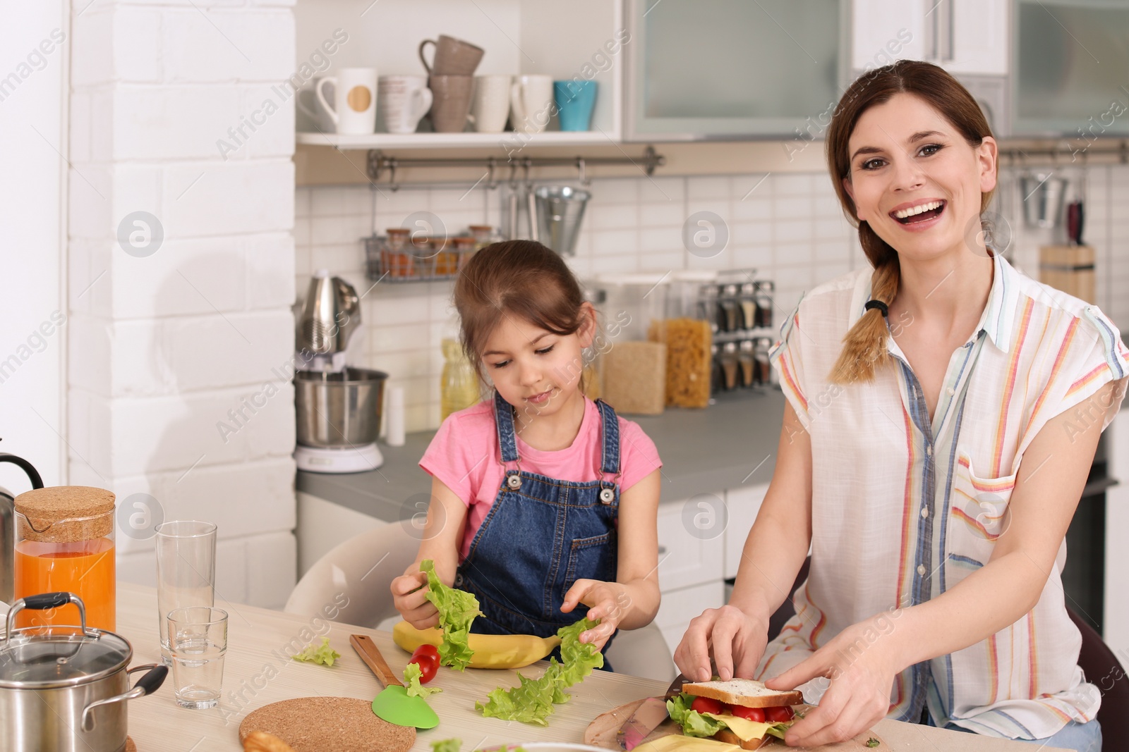 Photo of Housewife with her daughter preparing dinner on kitchen