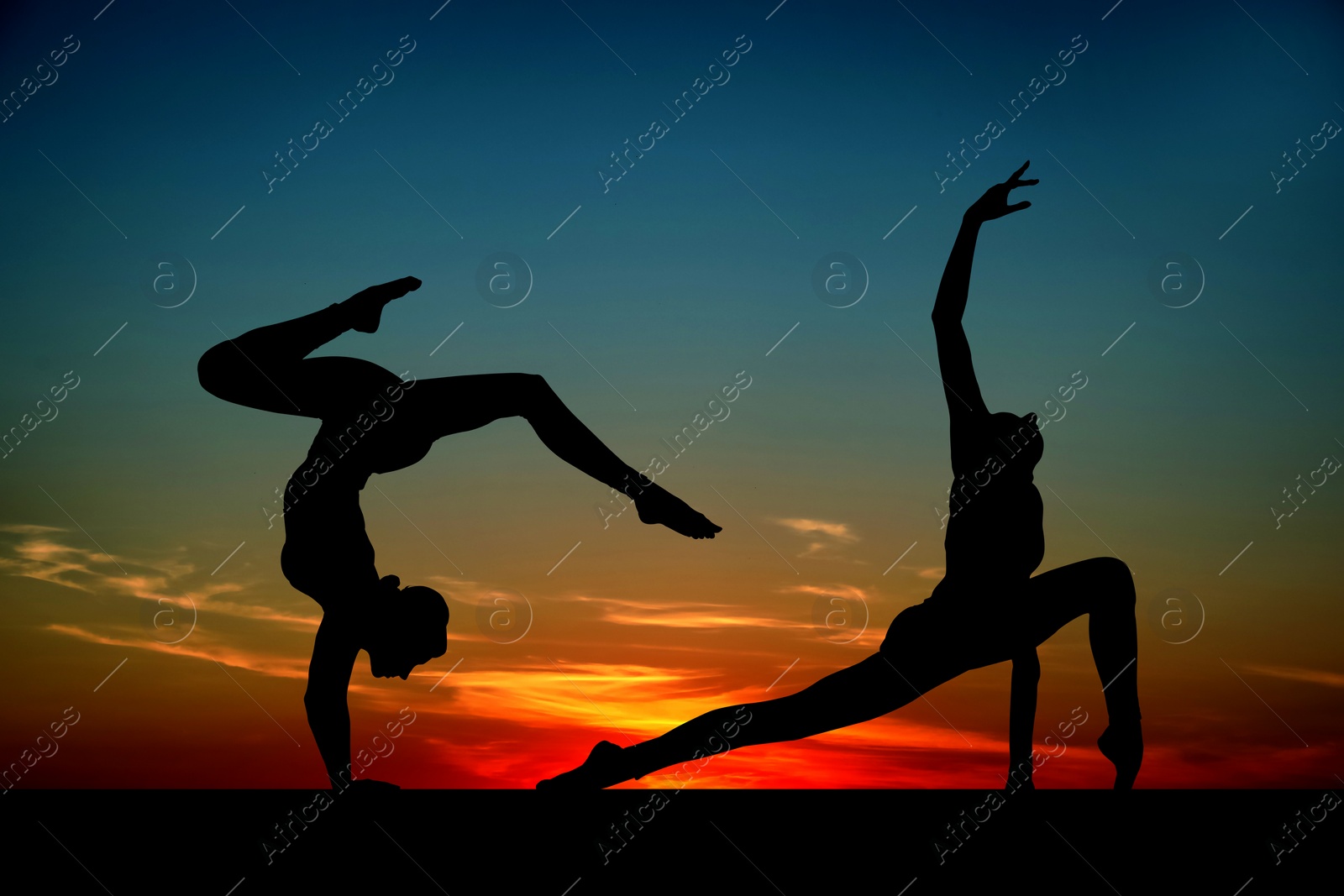 Image of Silhouettes of professional gymnasts exercising against beautiful sky