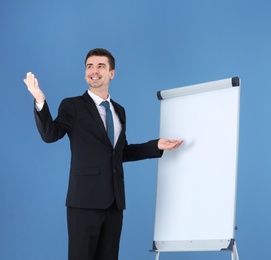 Photo of Business trainer giving presentation on flip chart board against color background