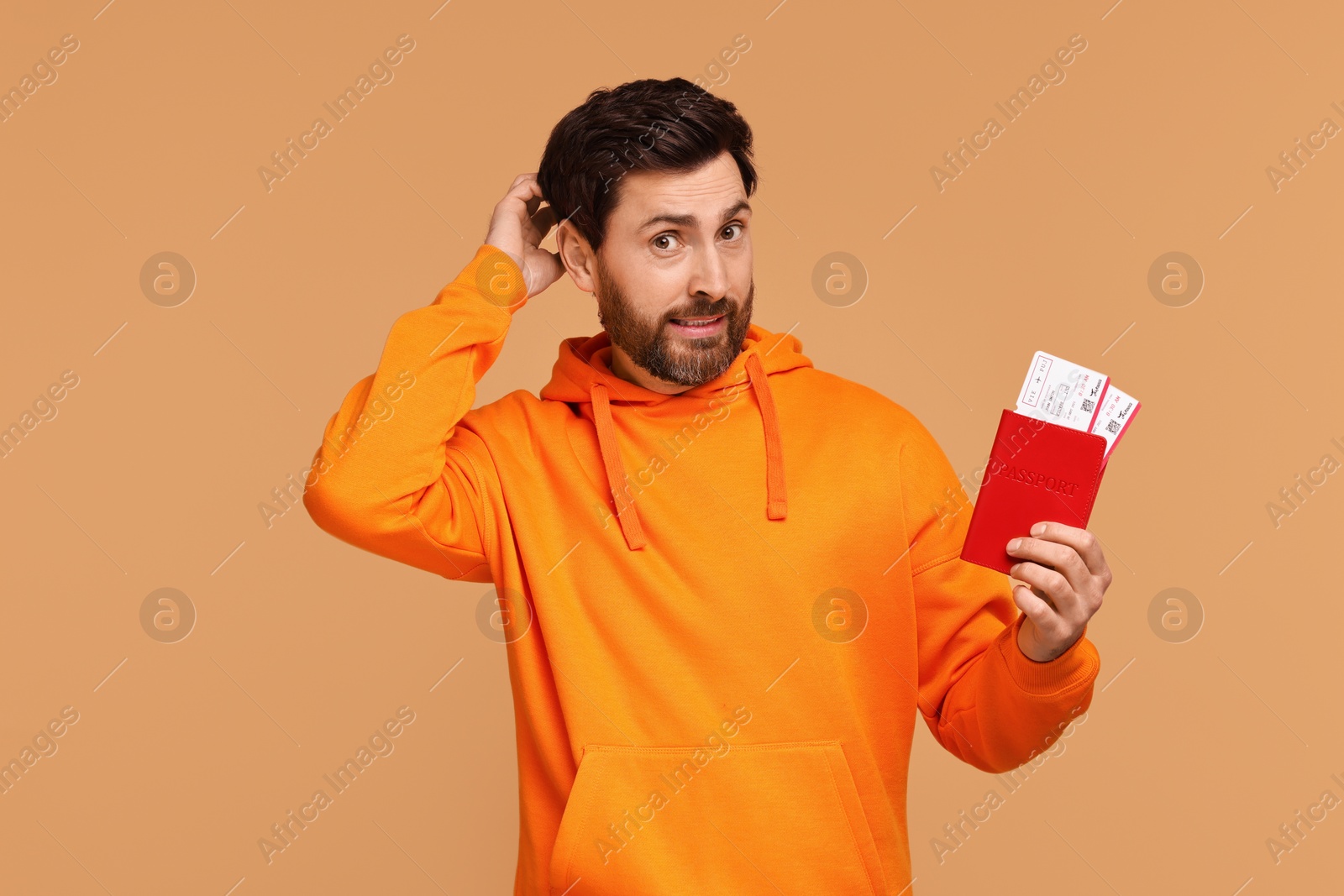 Photo of Thoughtful man with passport and tickets on beige background