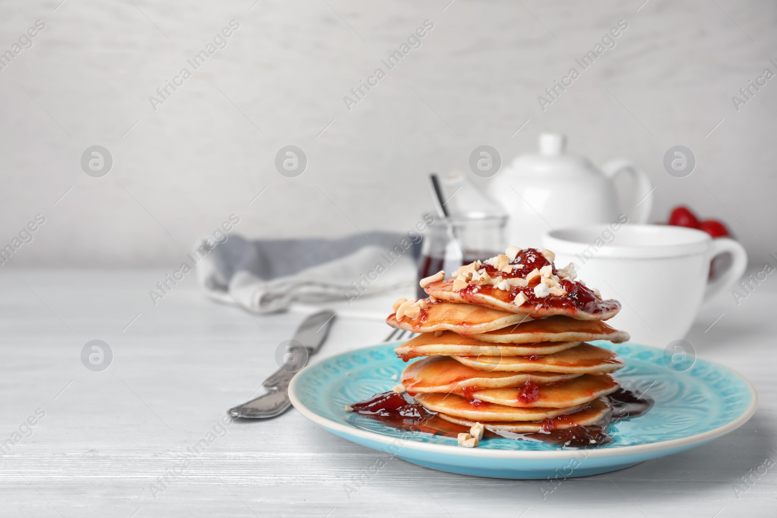 Photo of Delicious pancakes with jam and nuts served for breakfast on table