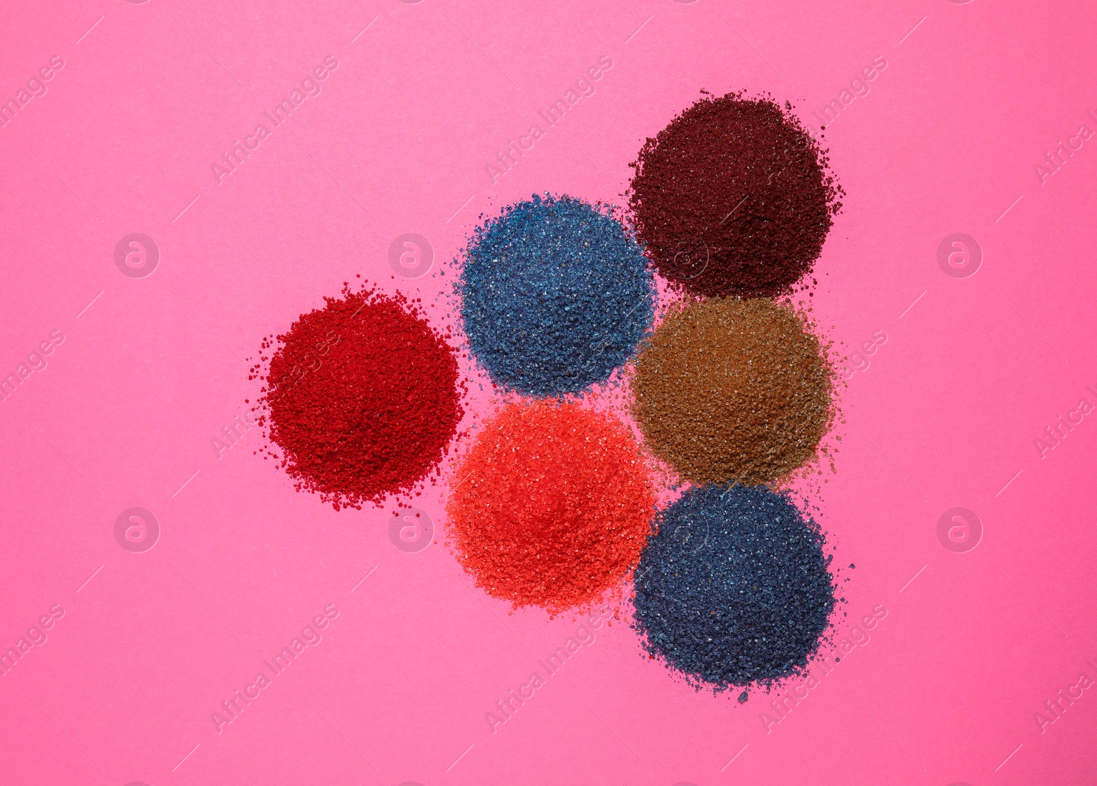 Photo of Heaps of different bright food coloring on pink background, flat lay