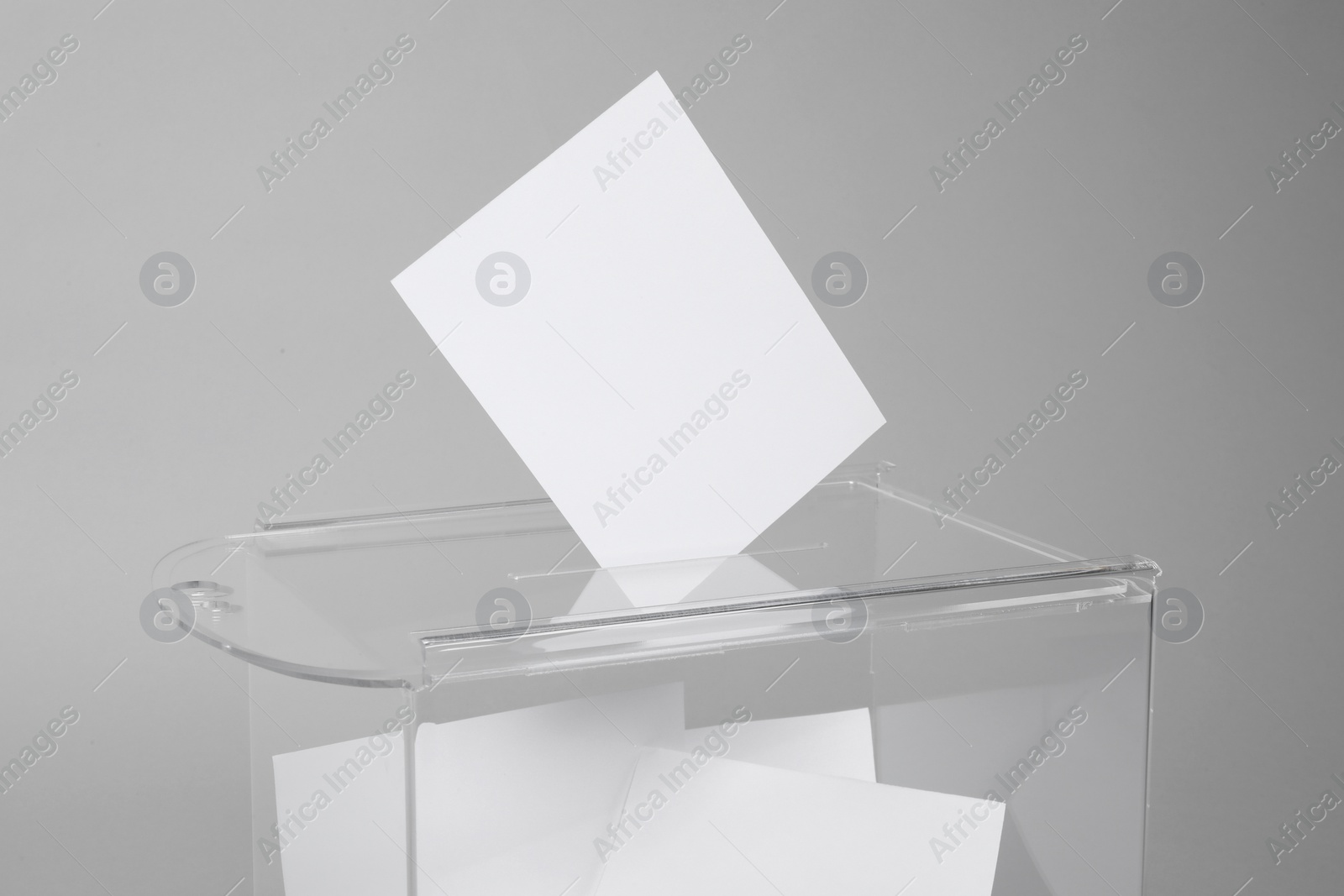 Photo of Ballot box with votes on light grey background. Election time