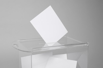 Photo of Ballot box with votes on light grey background. Election time