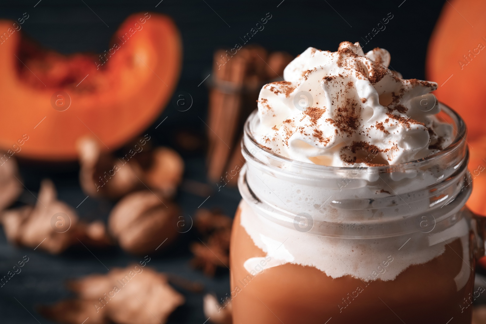 Photo of Delicious pumpkin latte in mason jar on table, closeup