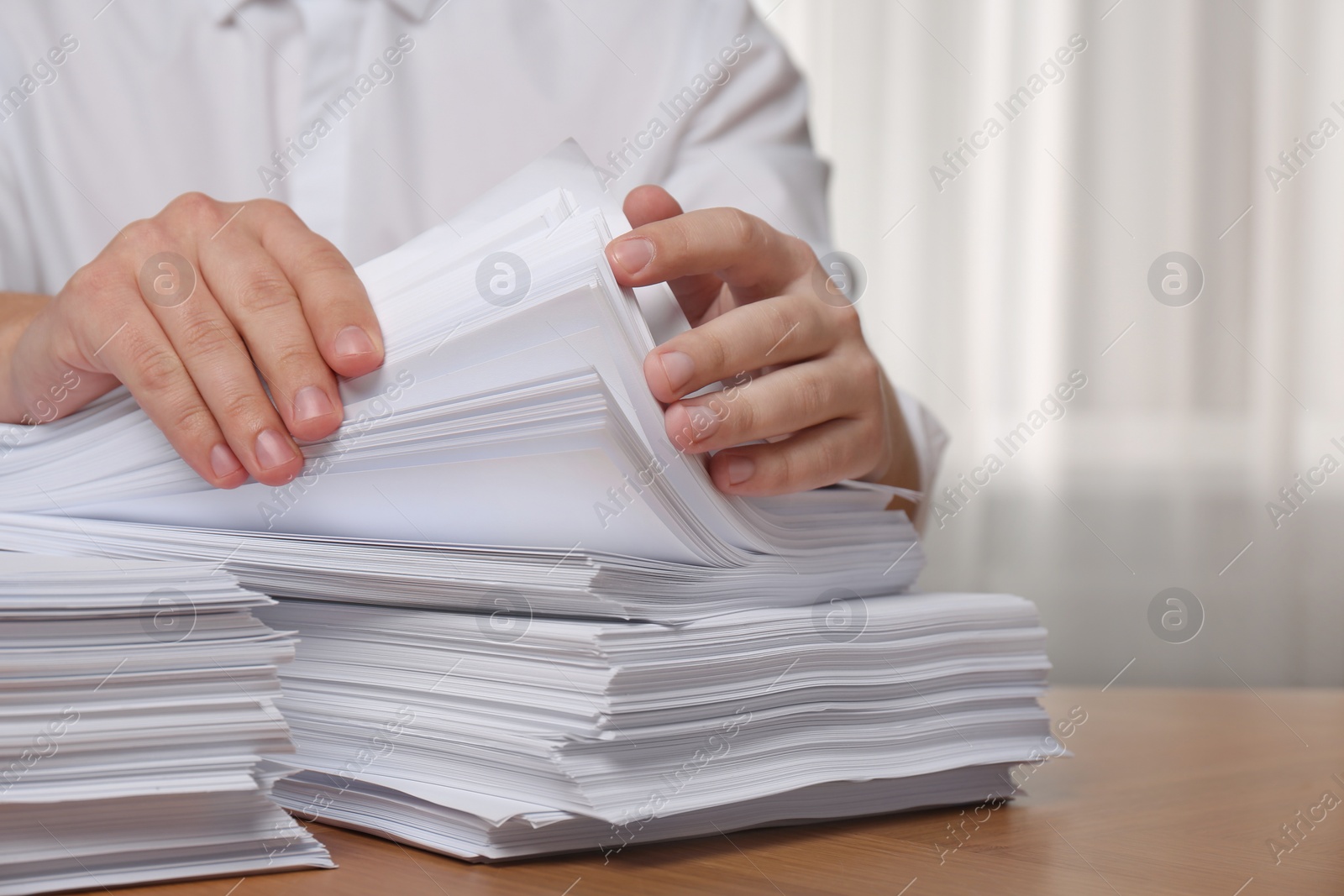 Photo of Man stacking documents at table in office, closeup