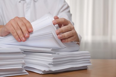 Photo of Man stacking documents at table in office, closeup