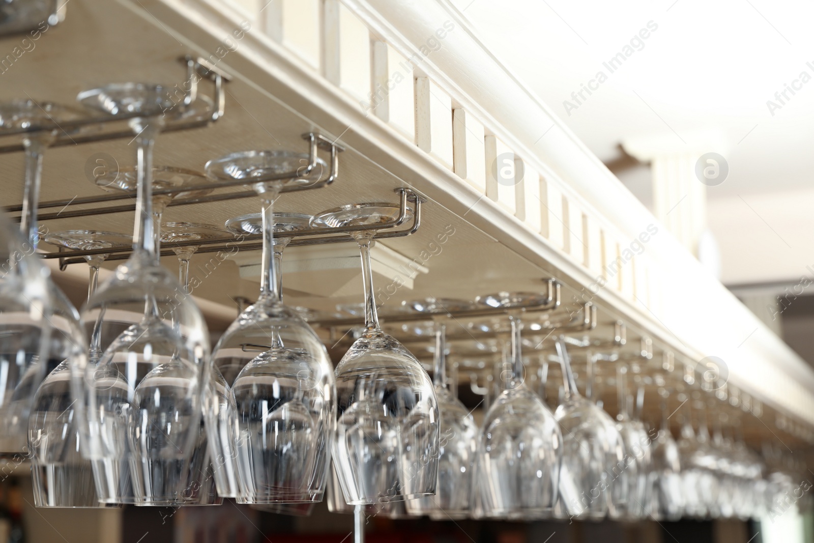 Photo of Set of empty clean glasses on bar racks