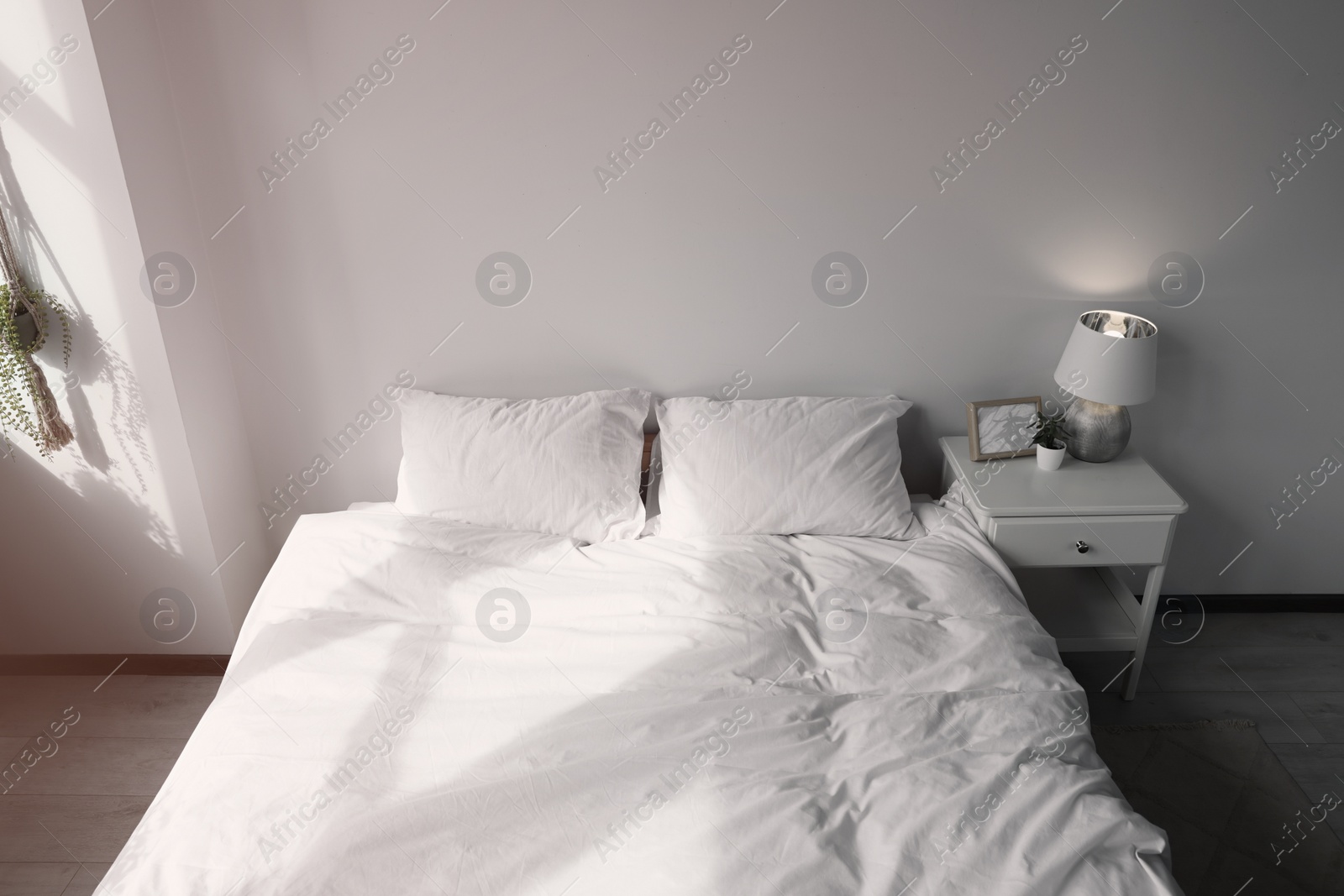 Photo of Large comfortable bed with soft pillows and blanket indoors