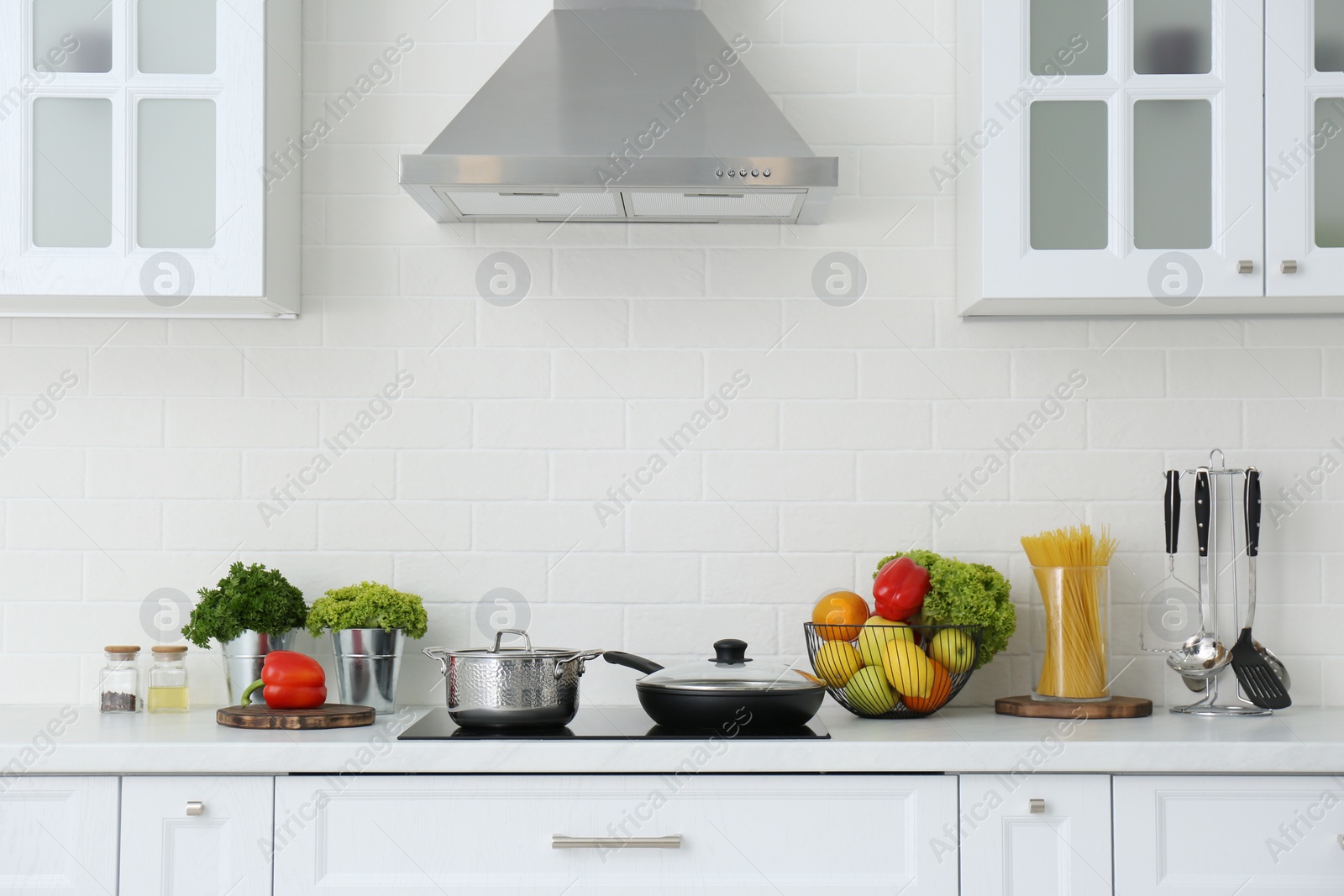 Photo of Counter with set of dishware, utensils and products in stylish kitchen interior