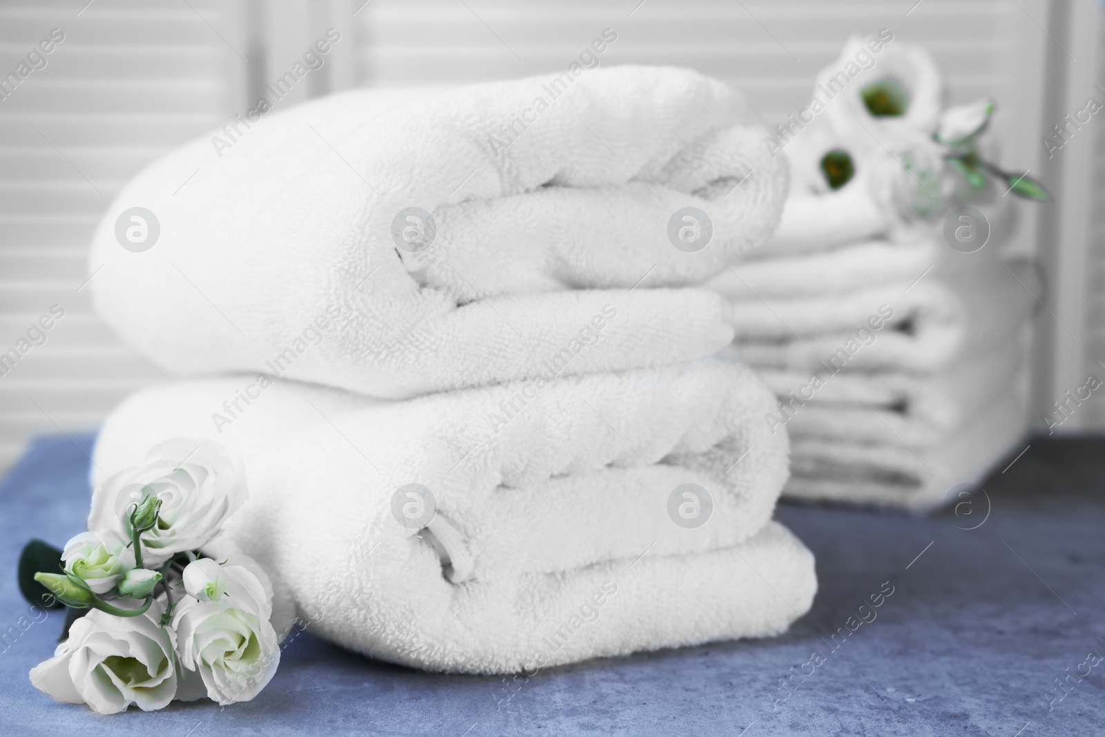 Photo of Folded towels and eustoma flowers on gray marble table