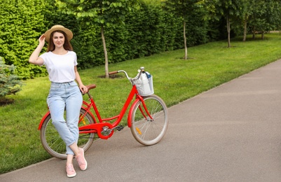 Photo of Young woman near modern color bicycle outside. Space for text