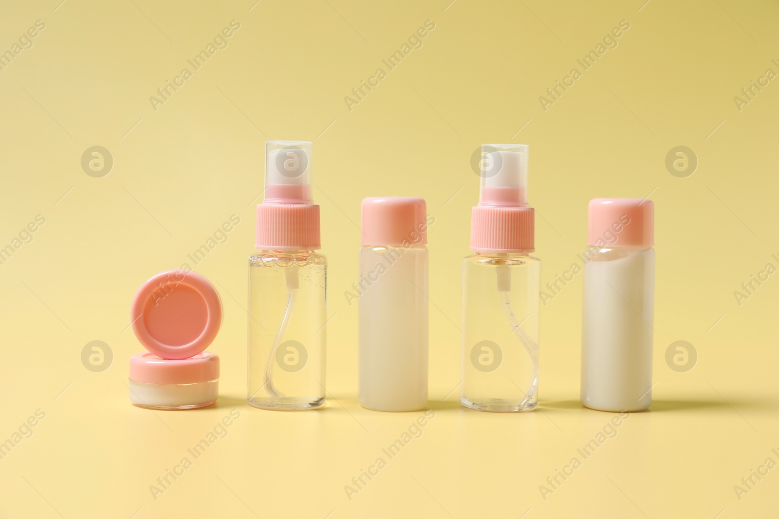 Photo of Cosmetic travel kit. Small containers of personal care products on yellow background