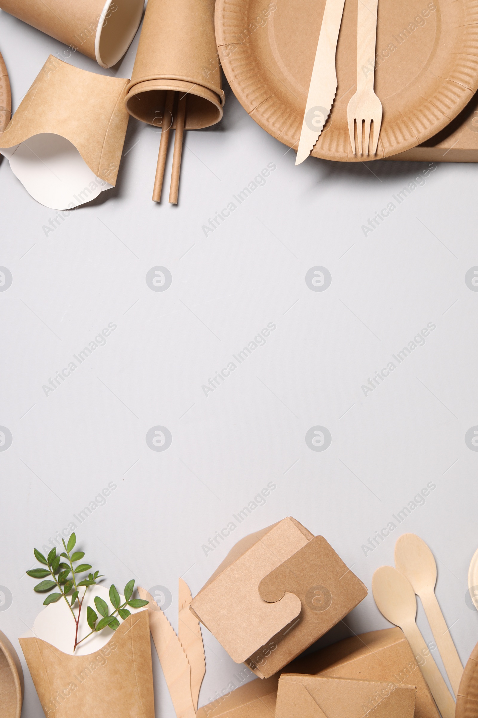 Photo of Eco friendly food packaging. Paper containers, tableware and twigs on light grey background, flat lay. Space for text